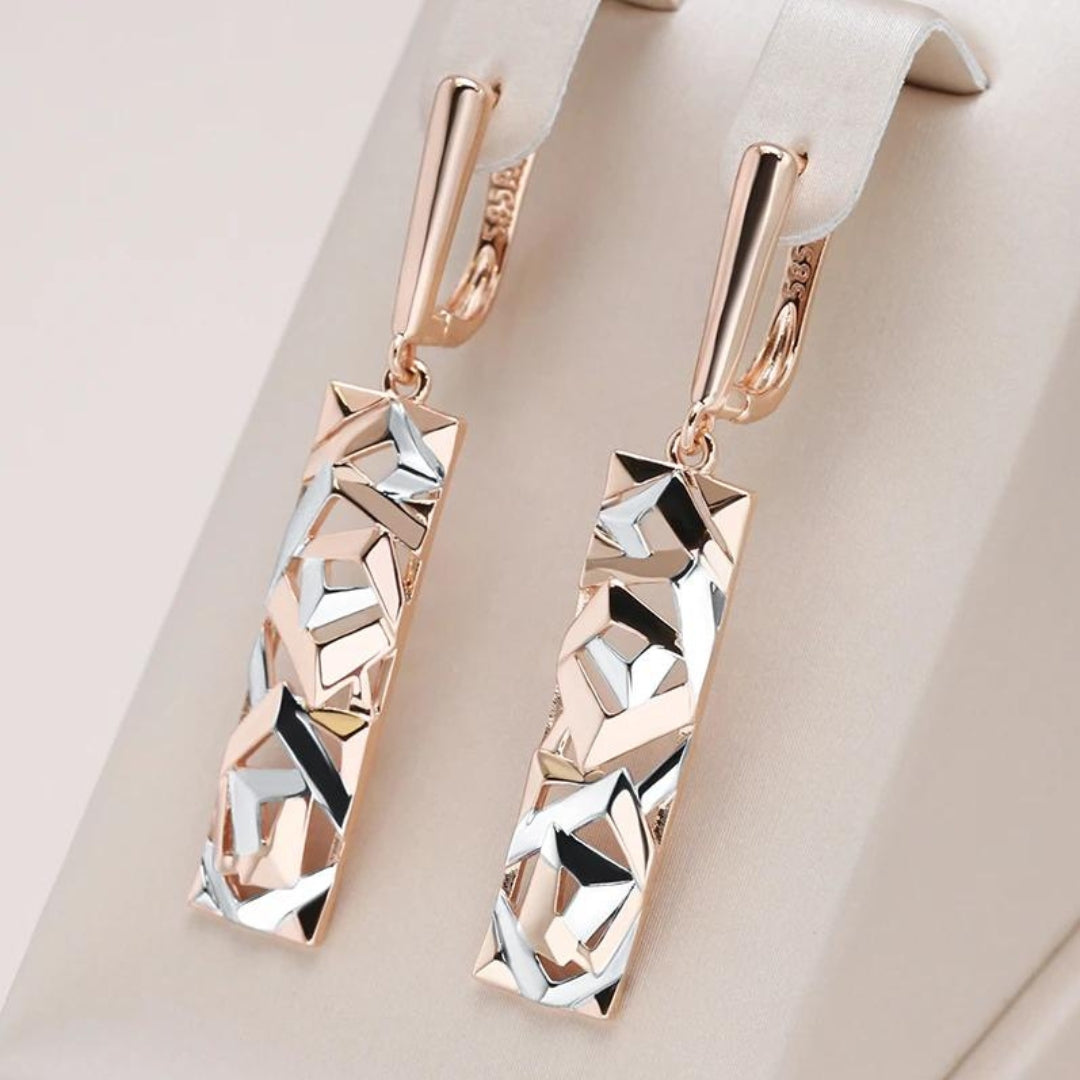 Rectangular gold and silver drop earrings with faceted geometric panels, close-up view