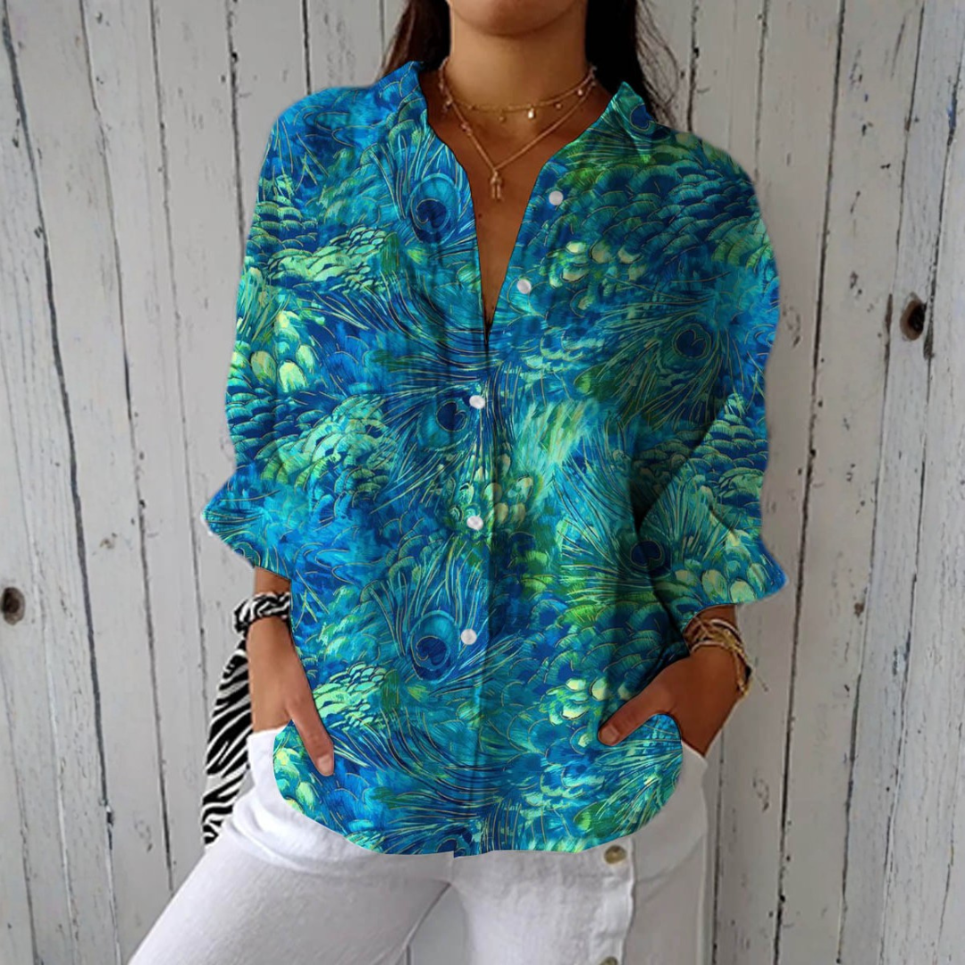Leila peacock feather print blouse in blue and green, front view with white trousers