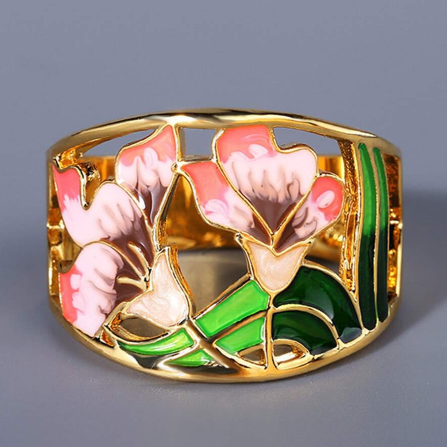 Gold enamel flower ring with pink blooms and green leaves, side view