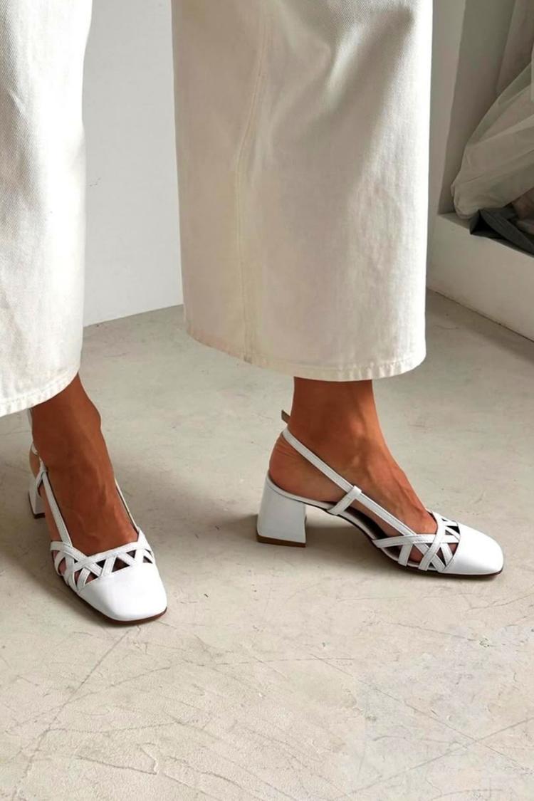 White square-toe cut-out slingback block heels worn with cream trousers, side view