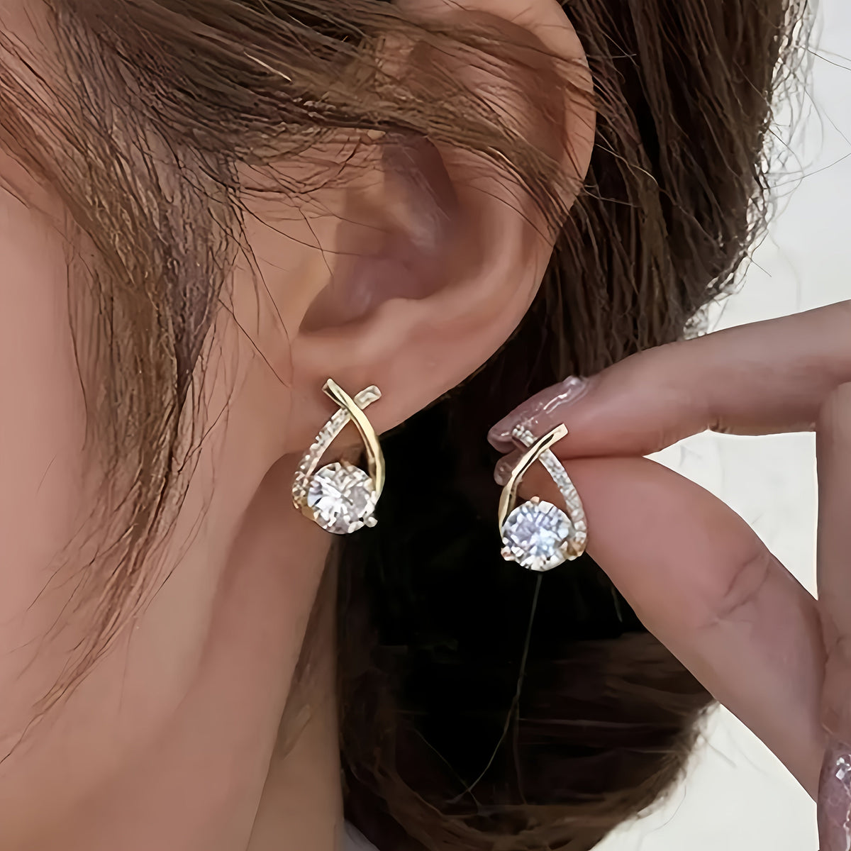 Leni gold cross earrings in gold, worn close-up on the ear