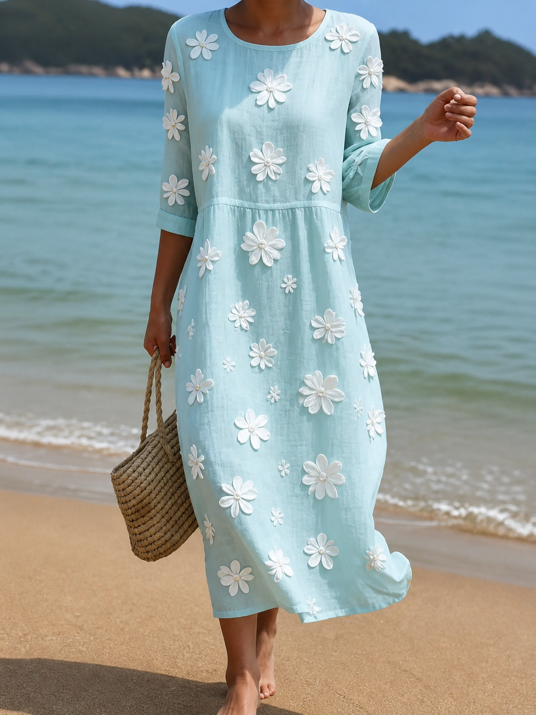Pale aqua midi dress with white daisy appliqués, full-length front view on the beach
