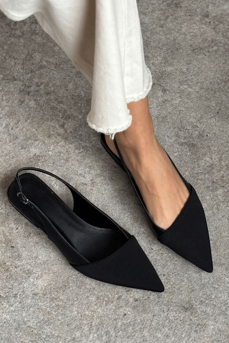 Black pointed slingback ballet flats, one worn and one showing the insole