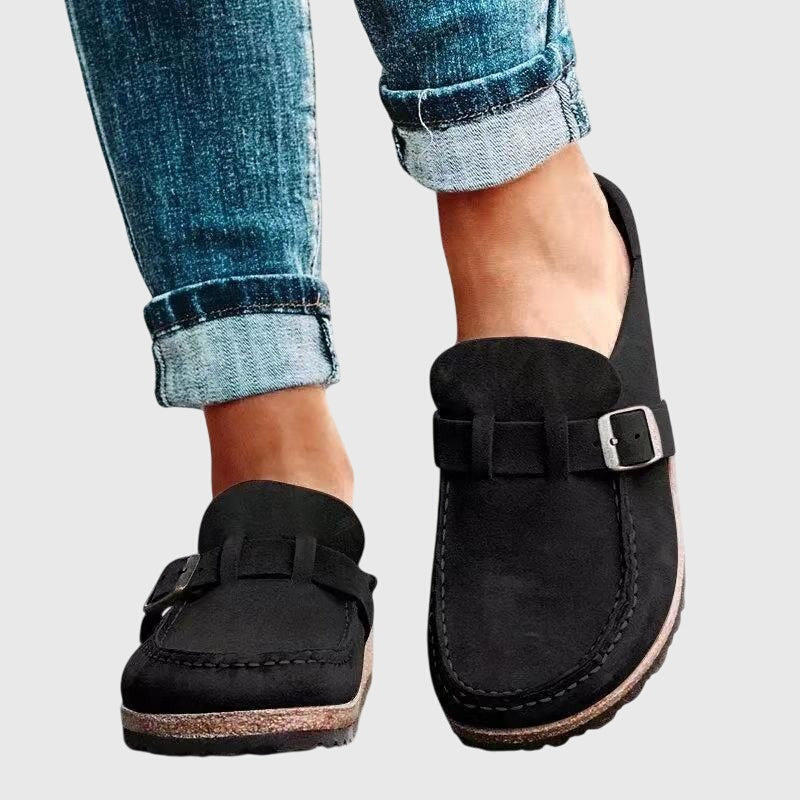Kendra clogs in black worn with jeans, front side view