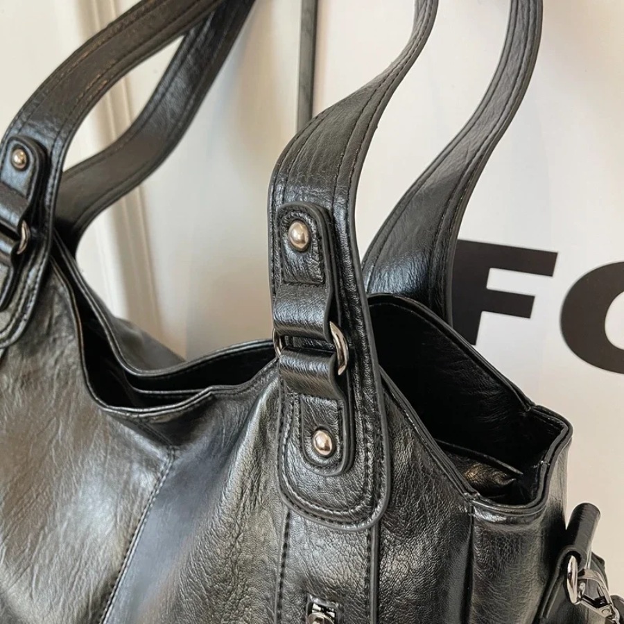 Close-up of black shoulder bag handles with studs and buckles