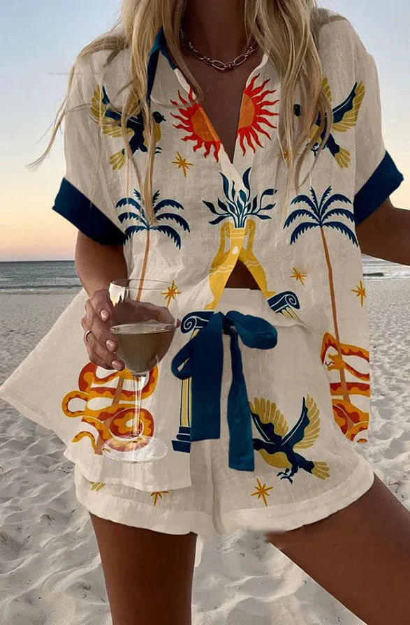 Soleil summer co-ord set in white with navy and gold print, worn on the beach
