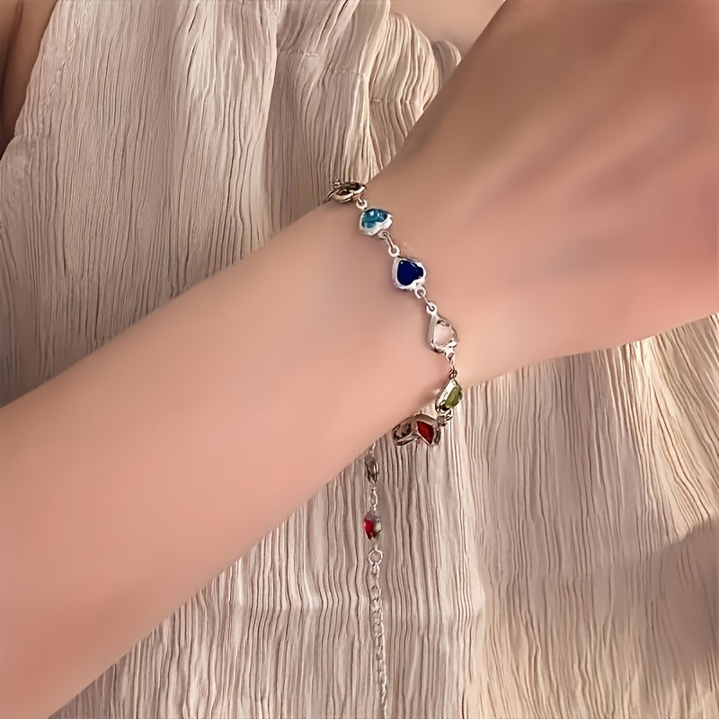Silver-tone heart bracelet with multicoloured stones worn on wrist
