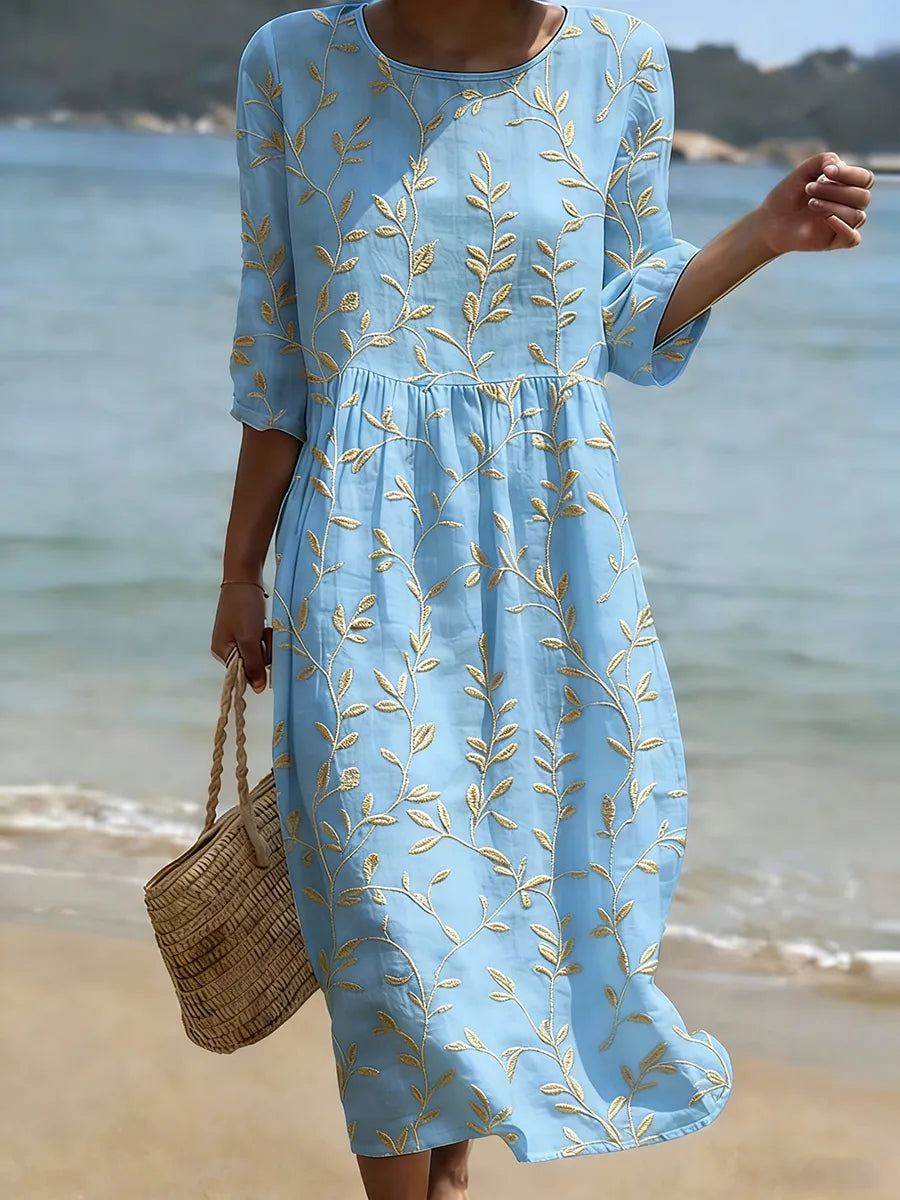 Blue floral print midi dress with golden leaf embroidery, full-length front view on the beach
