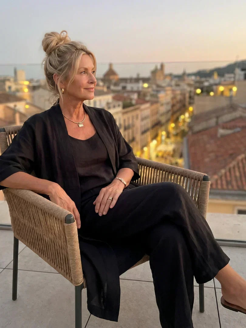 Lorrin three-piece set in black worn seated on a rooftop terrace