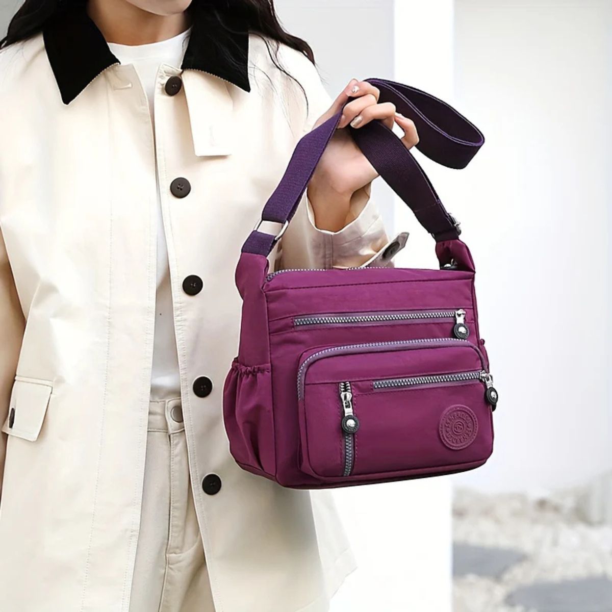 Evelisse shoulder bag in purple held by its strap, close-up view