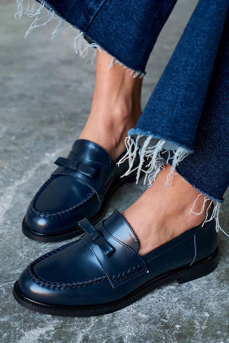 Navy bow loafers in close-up, showing stitched moccasin seam and glossy upper