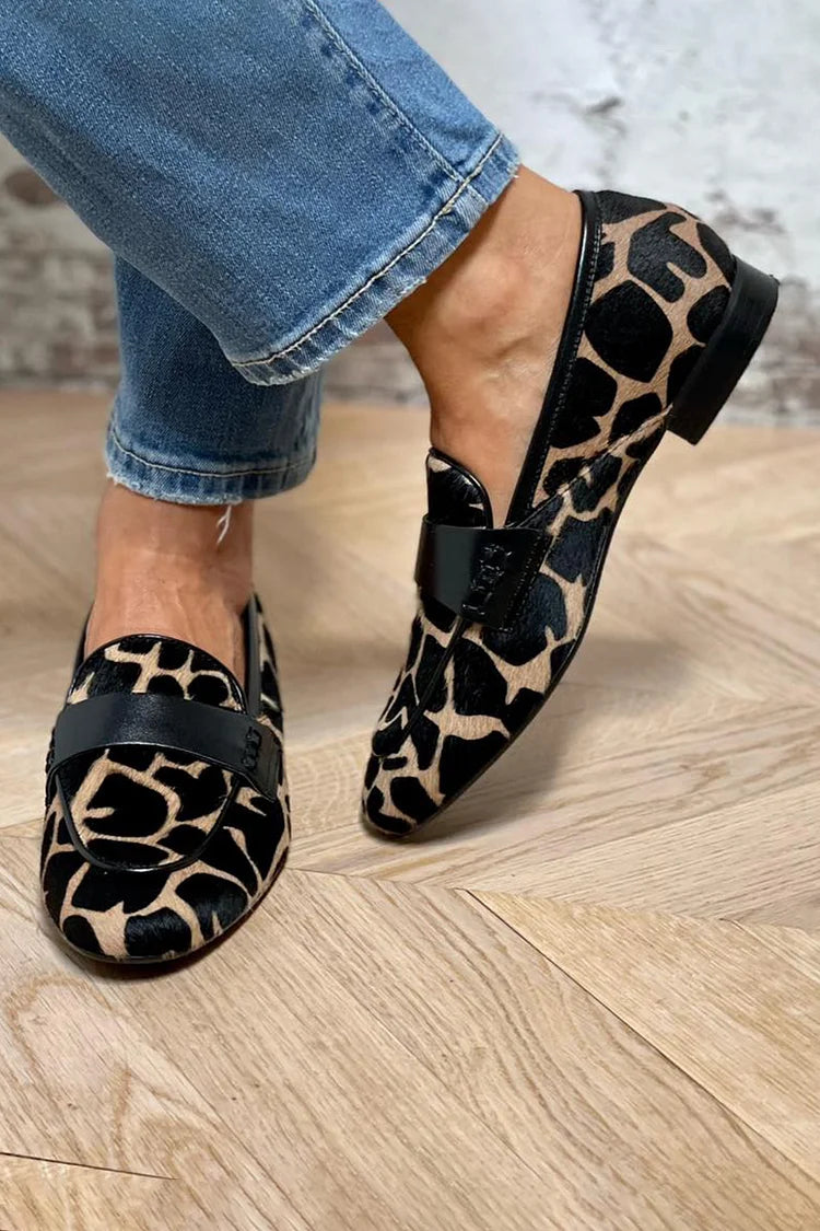 Cow print loafers with black trim band, worn top view