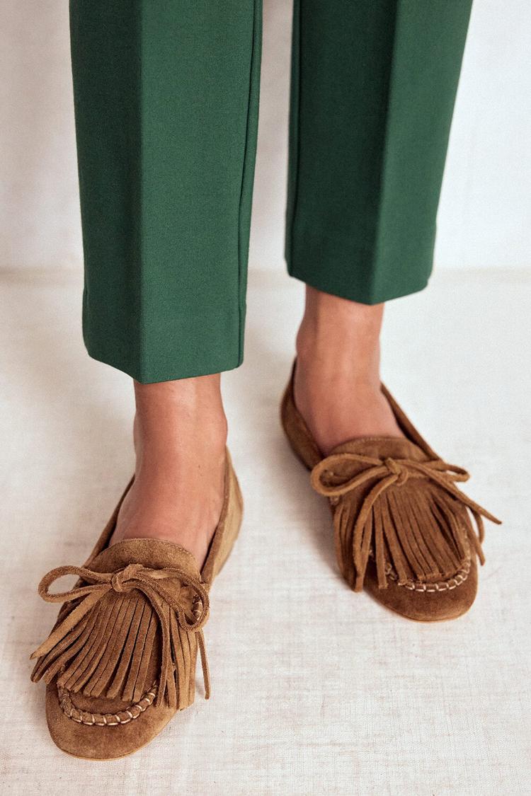 Camel fringed loafers worn with green trousers, front view standing