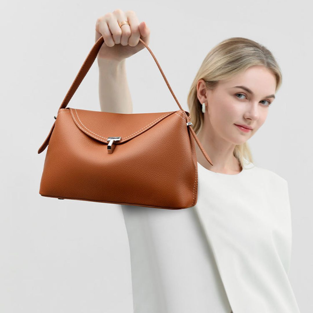 La Divine handbag in brown held by the shoulder handle