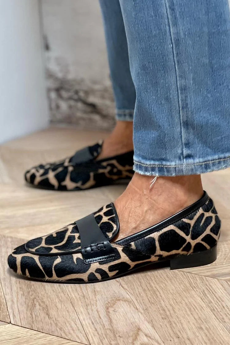 Cow print round-toe loafers in black, close side view on model