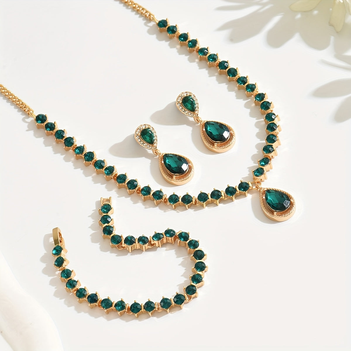 Close-up of gold-toned green crystal necklace, earrings and bracelet
