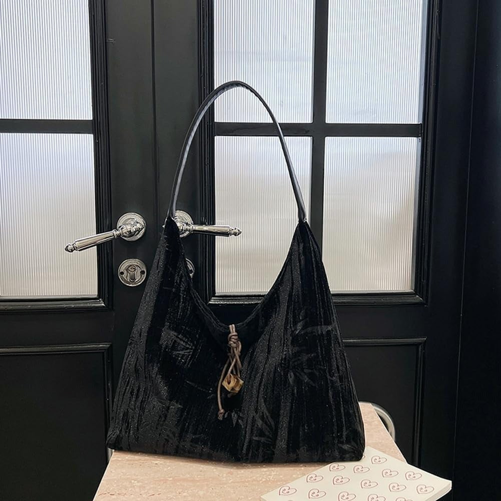 Amélie shoulder bag in black hanging from a dark door handle