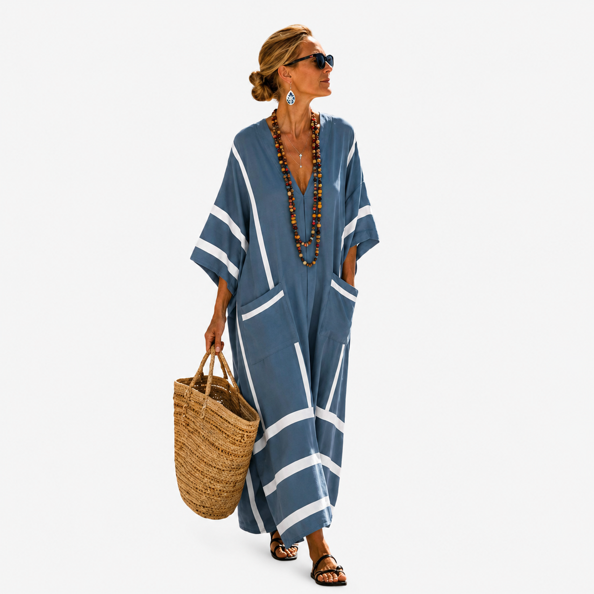 Long kaftan in blue with white stripes, full-length front view with straw bag