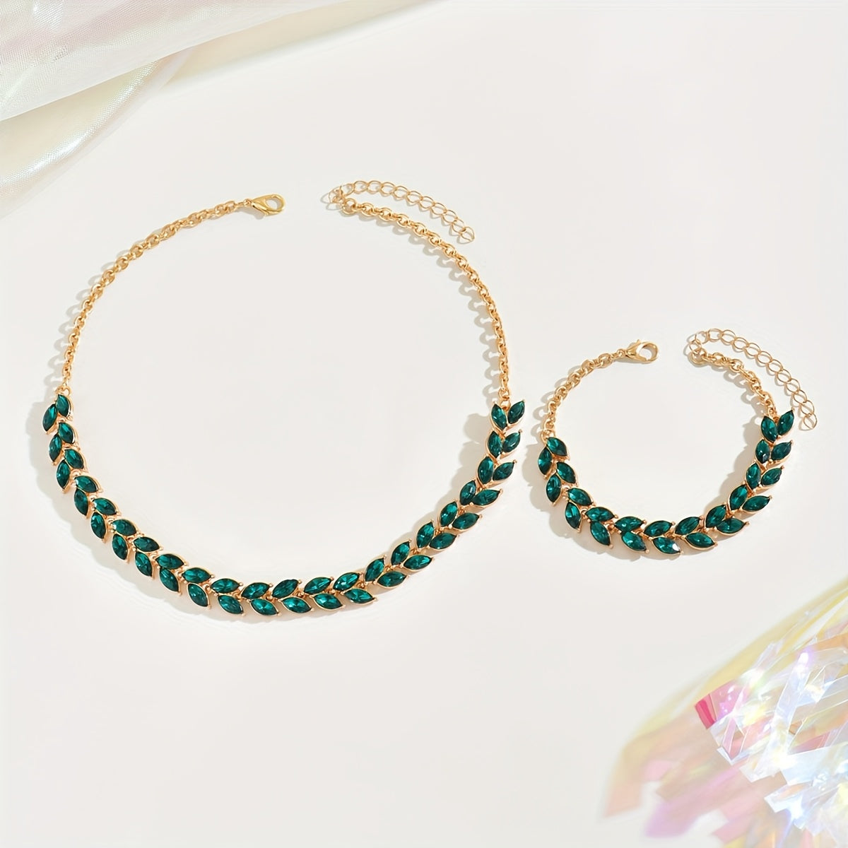 Green crystal necklace and bracelet set laid flat on pale background