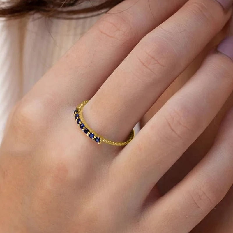 Seven-stone gold ring worn on a hand, close-up view