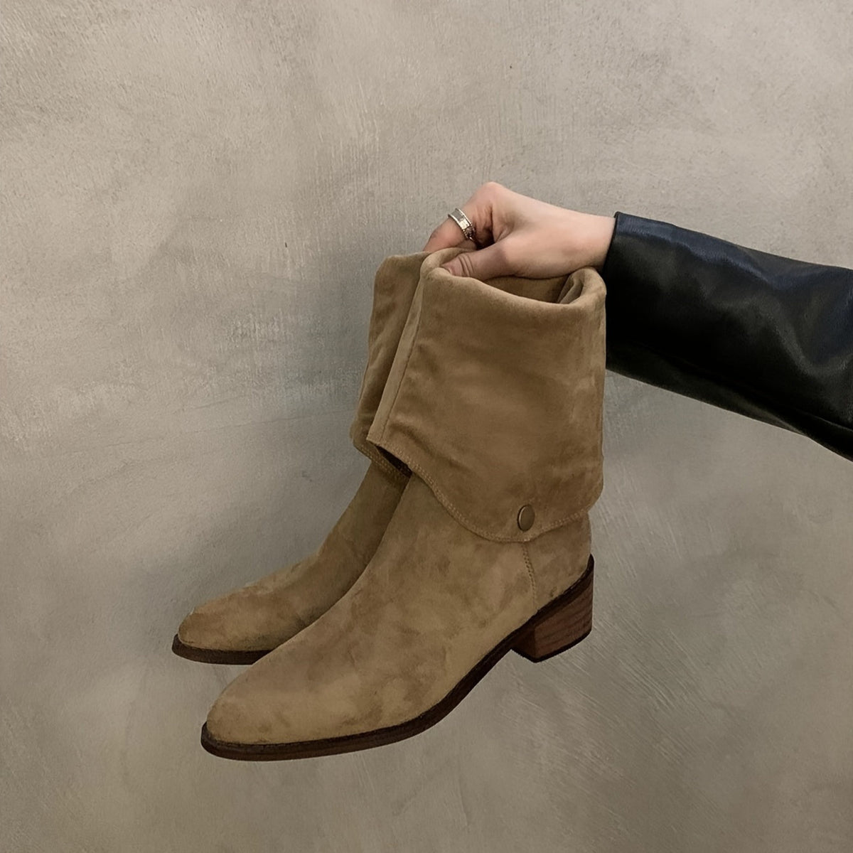 Evadne V-shape boot in khaki held in hand, folded shaft and stud detail