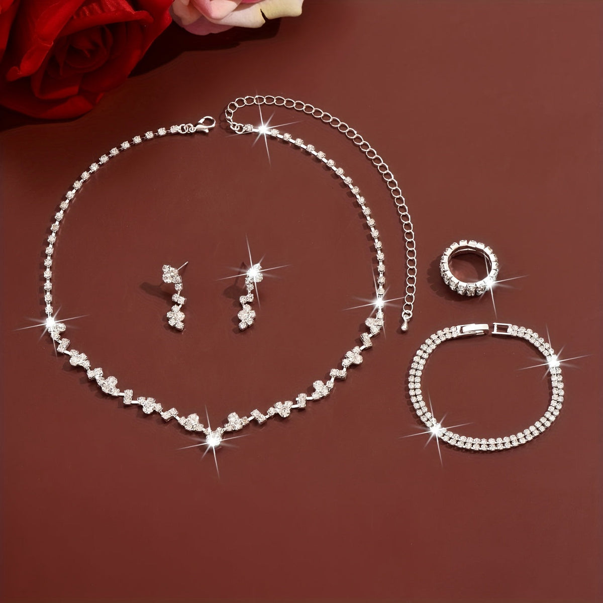 Silver four-piece jewellery set laid flat showing necklace, earrings, ring and bracelet