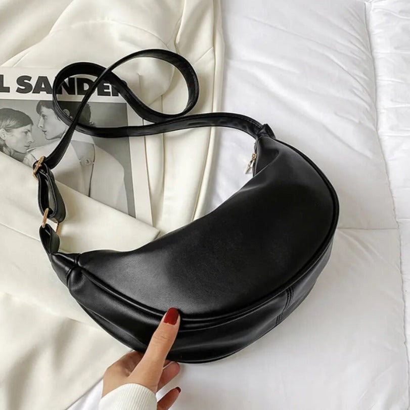 Maribel petite crescent bag in black laid flat with strap coiled
