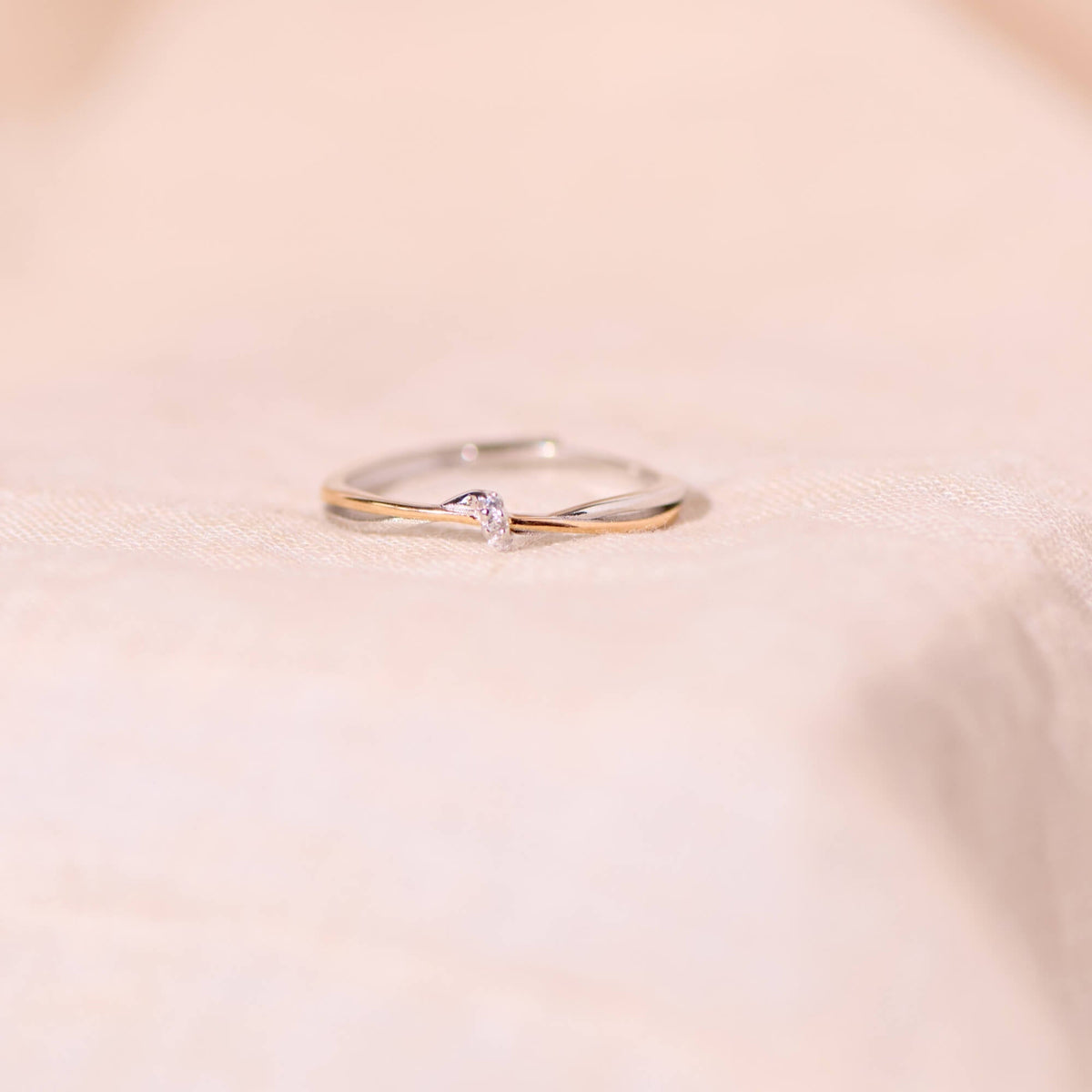 Two-tone infinity twist ring with tiny stone on soft fabric