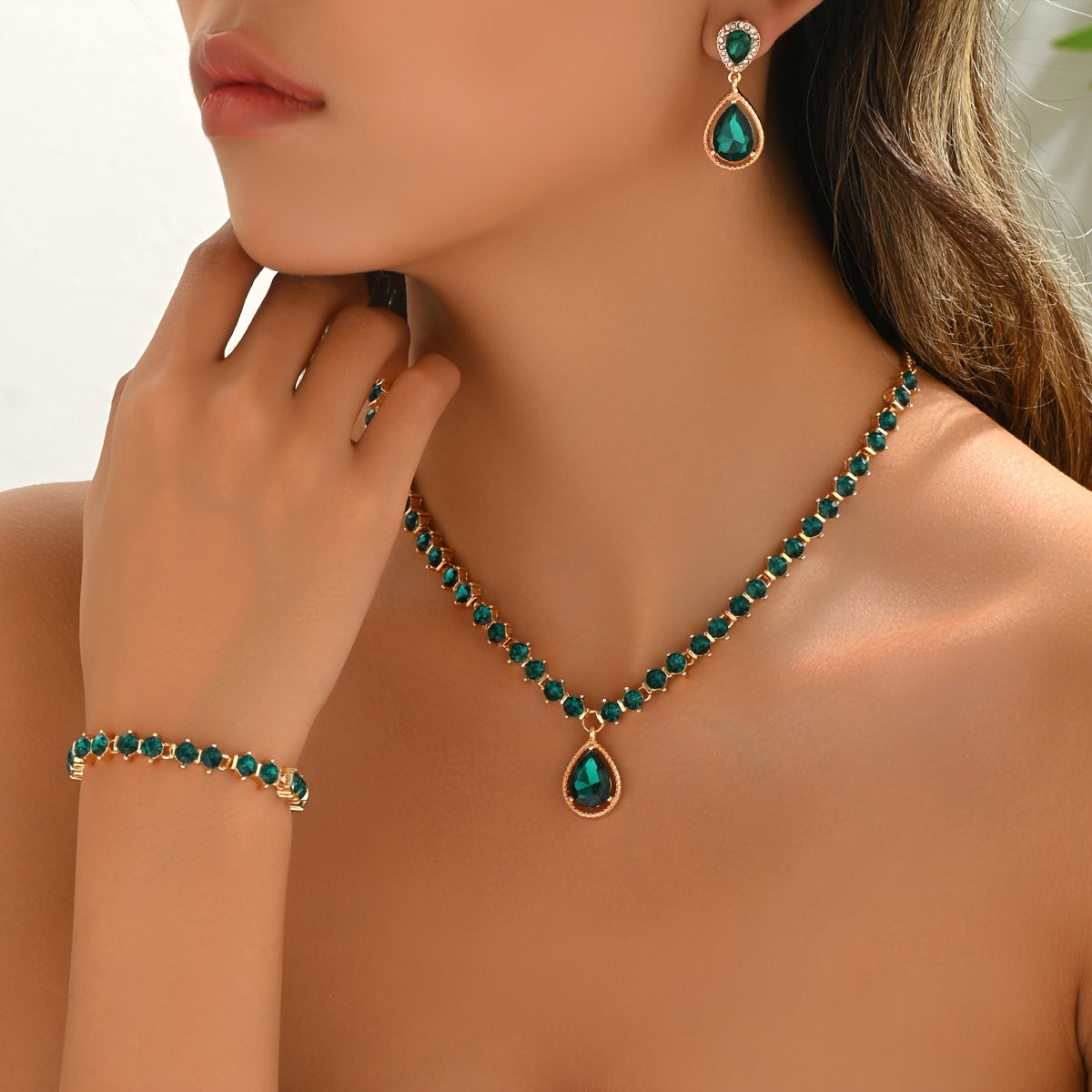 Model wearing green teardrop crystal necklace, drop earrings and bracelet