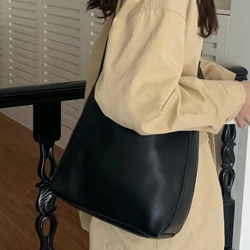 Isolde shoulder bag in black carried at the side