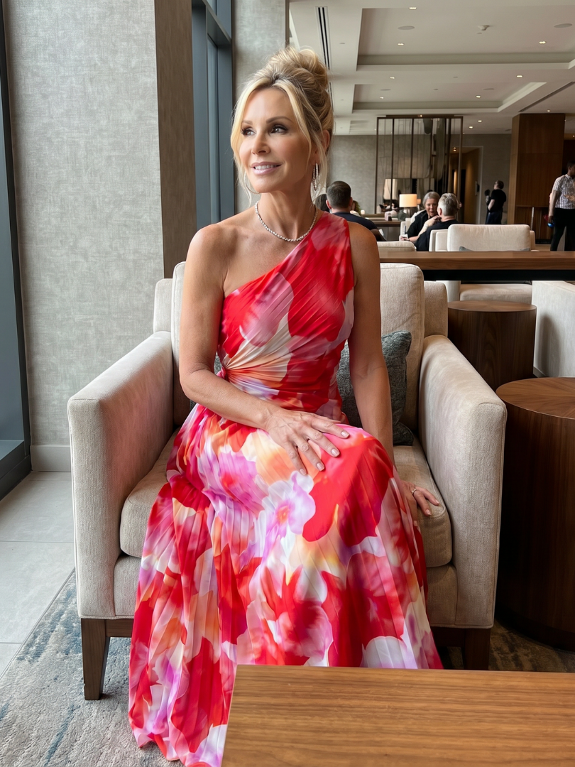 Taya floral midi dress worn seated in a hotel lounge, three-quarter view