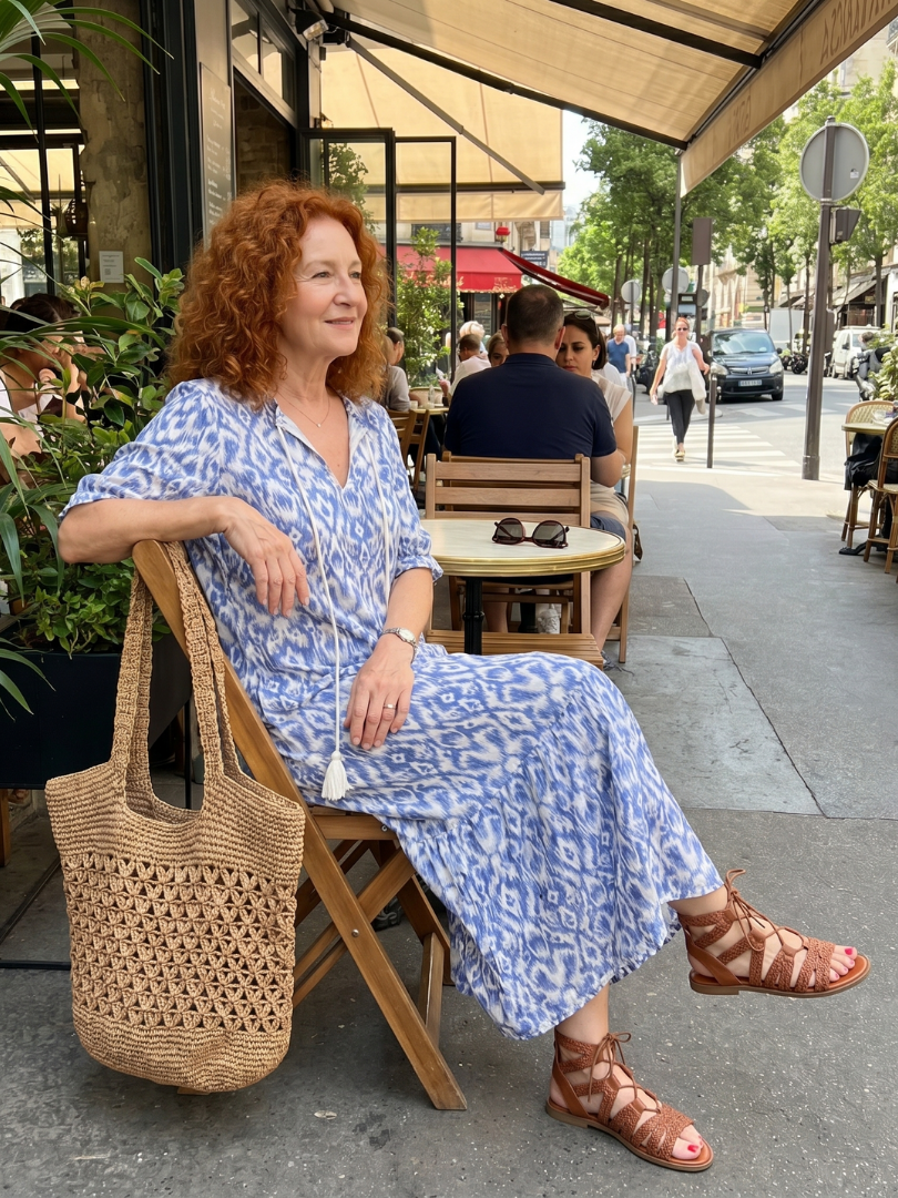 Ottoline printed midi dress in blue, worn seated at a pavement cafe