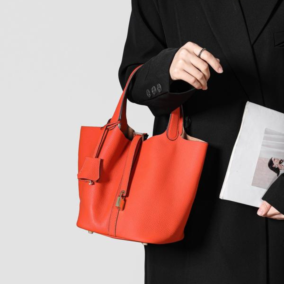 Kate lock bag in orange, side view held in hand