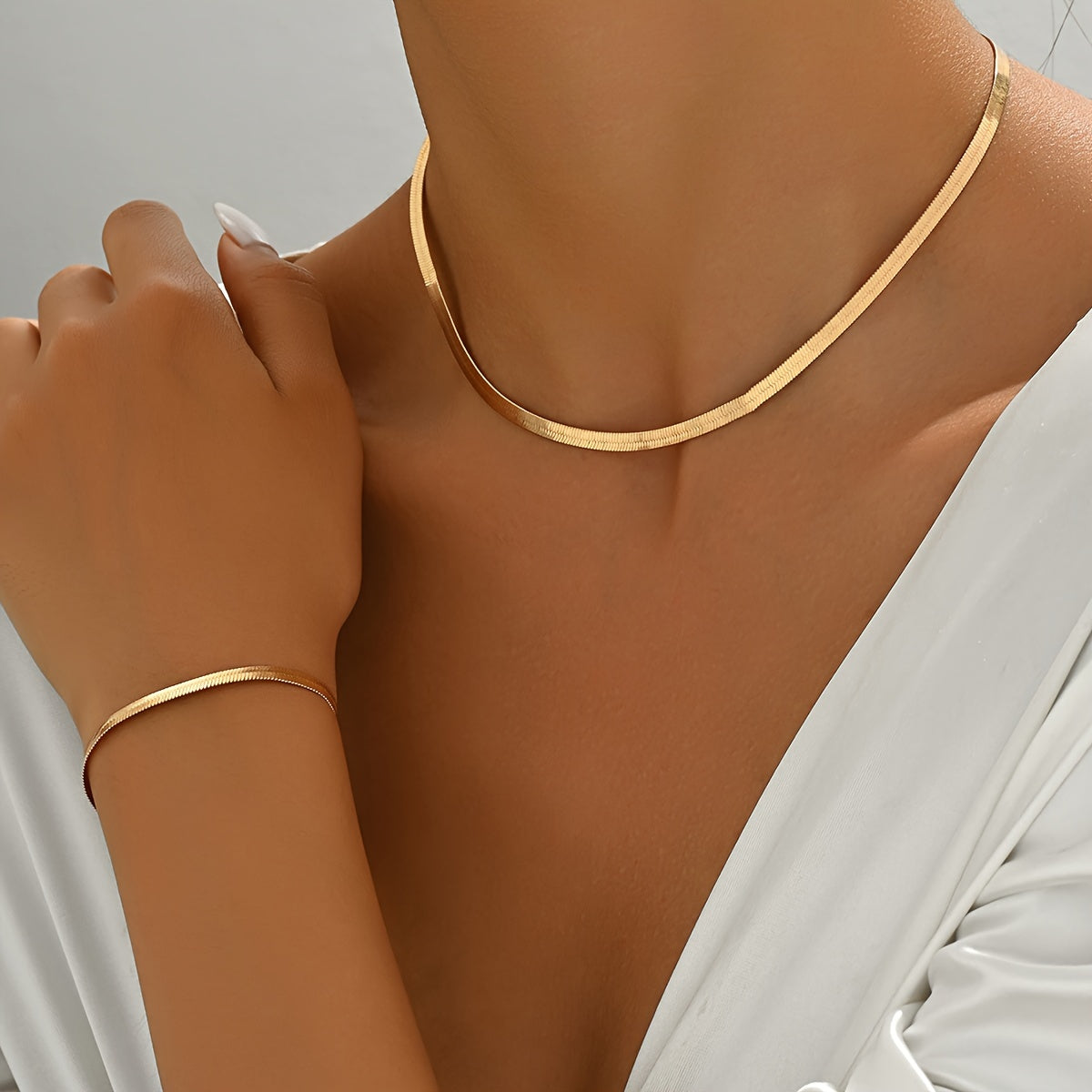 Gold collar necklace and slim bracelet styled with a white wrap blouse