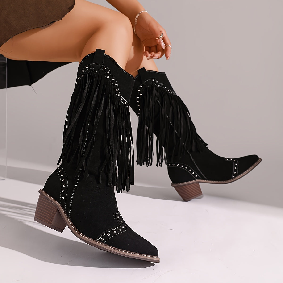 Marigold tassel-studded boots in black, worn seated side view