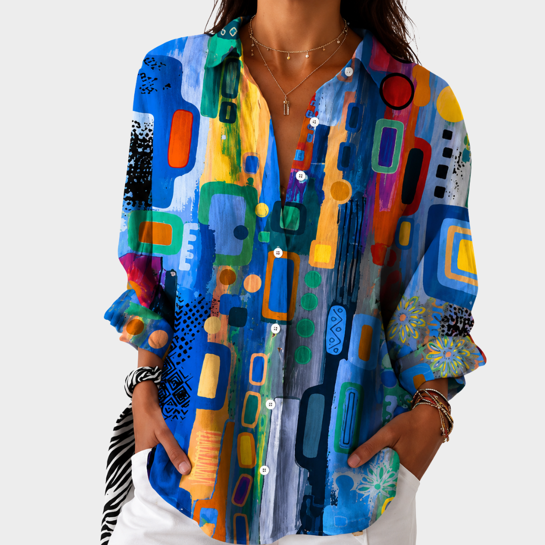 Bold colour mosaic blouse in multicoloured blue print, front view worn with white trousers