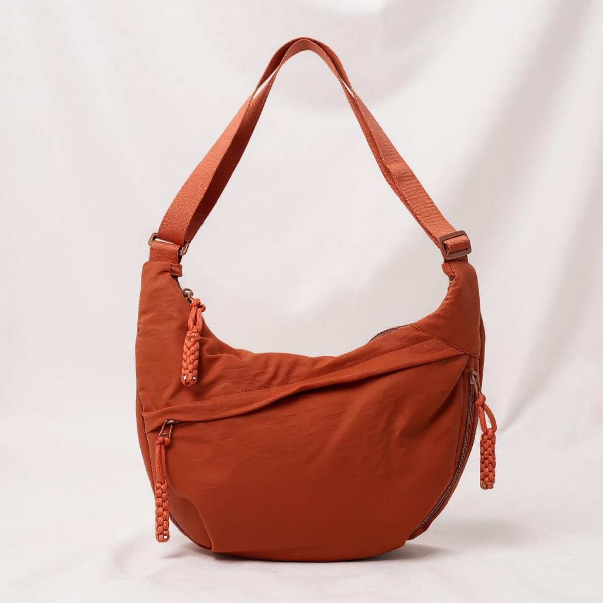 Clementine crescent shoulder bag in orange, front view with braided zip pulls