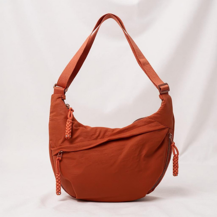 Clementine crescent shoulder bag in orange, front view with braided zip pulls