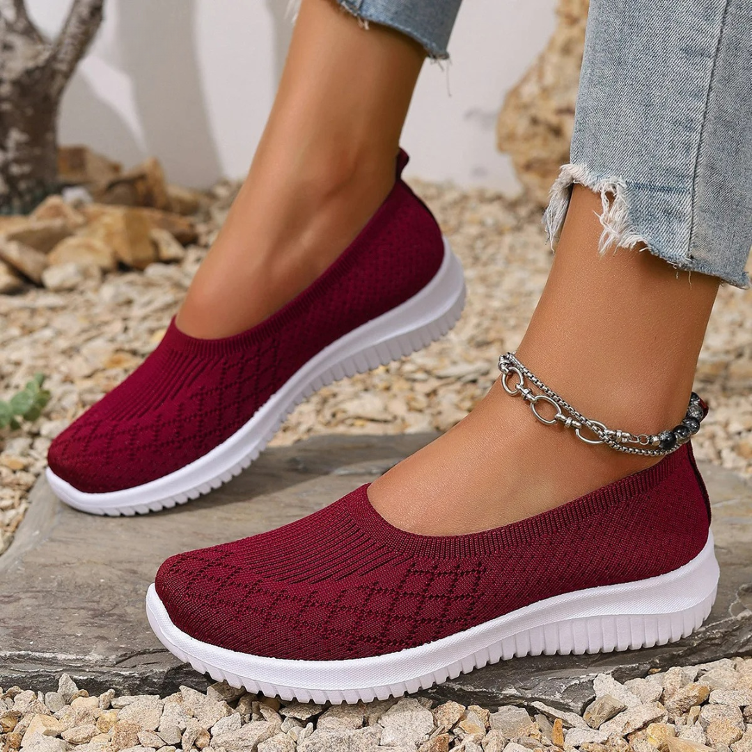 Estella slip-on shoes in red, worn outdoors, angled view