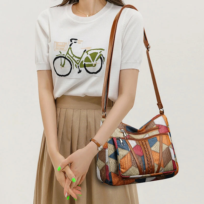 Close-up of patchwork handbag worn cross-body over a pleated skirt