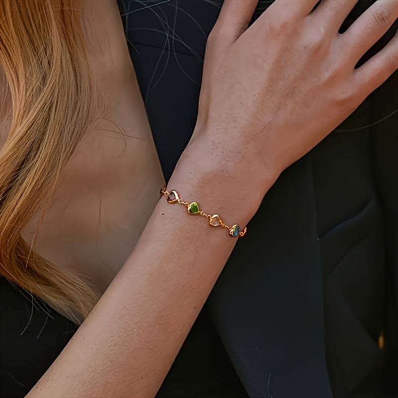 Gold multicoloured heart bracelet worn with dark outfit, arm view