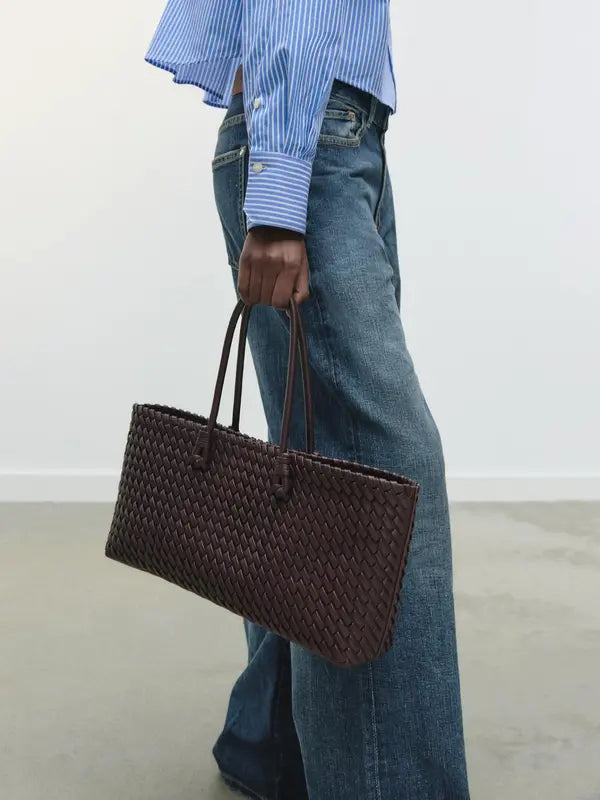 Lindsay woven tote bag in burgundy carried by hand with jeans