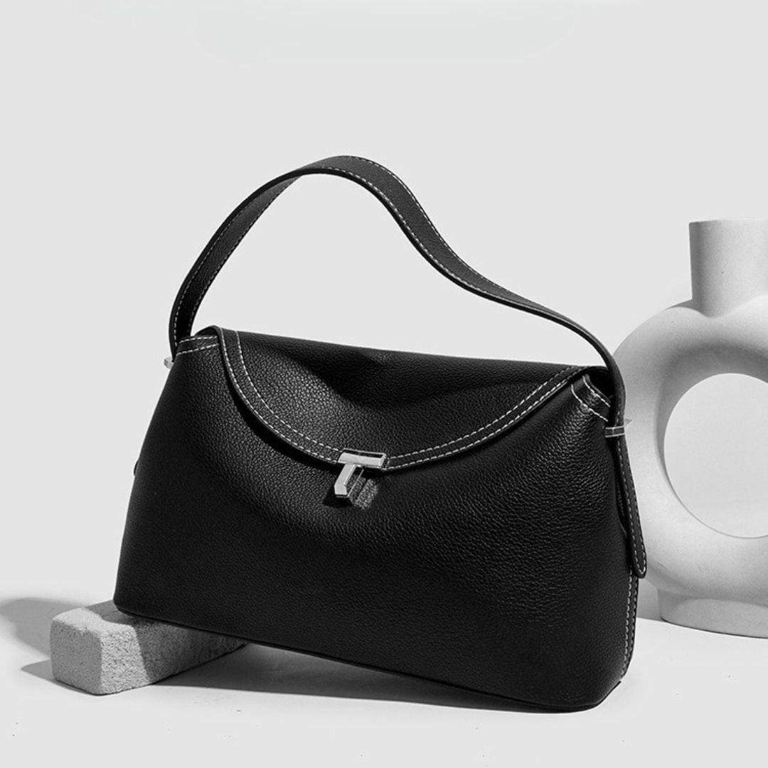 La Divine handbag in black, angled view showing curved flap