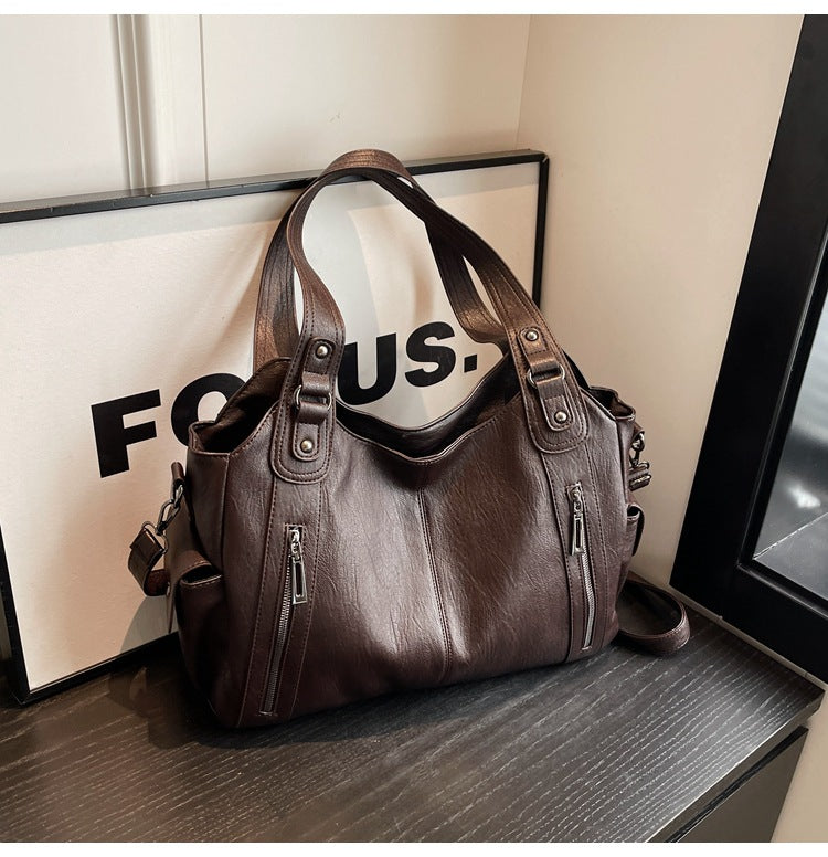 Rae leather handbag in brown, angled view on a dark shelf