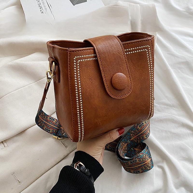 Ethel shoulder bag in brown held in hand, close view of stud detail