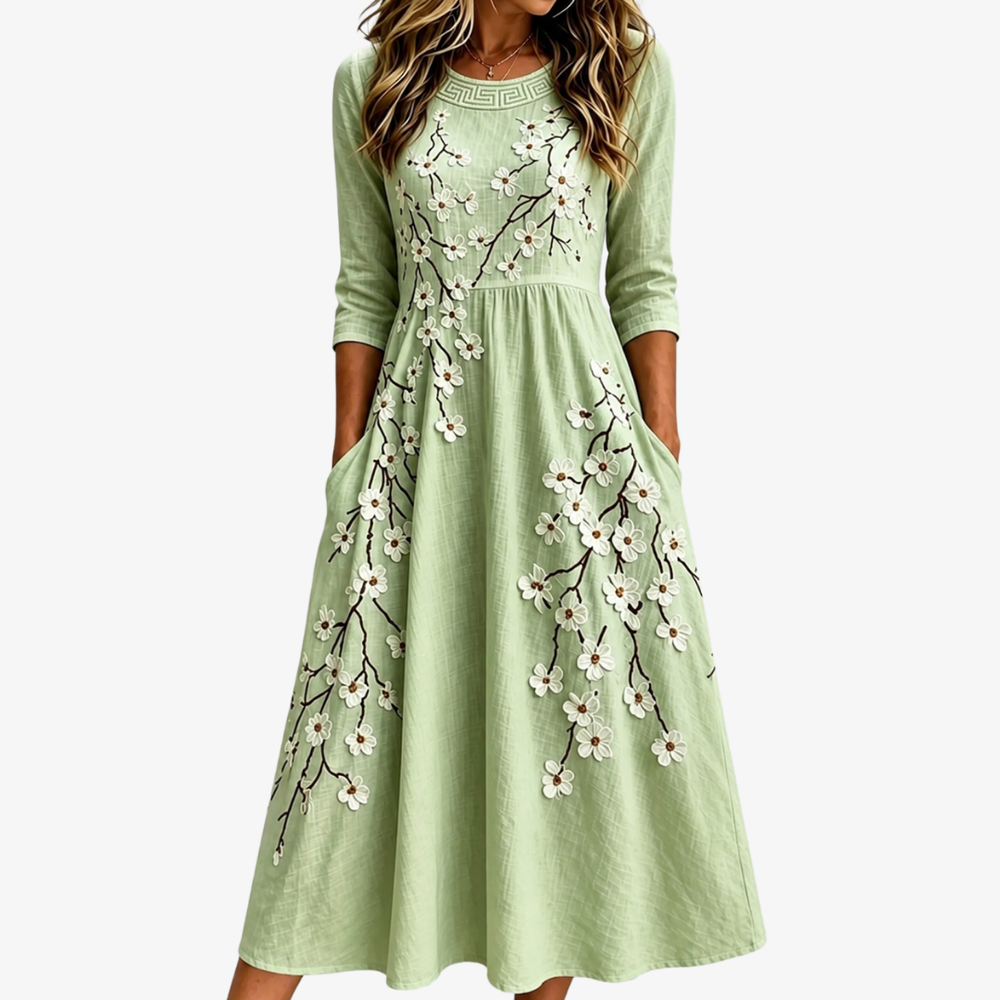 Sage green floral midi dress with blossom branch pattern and side pockets, front view
