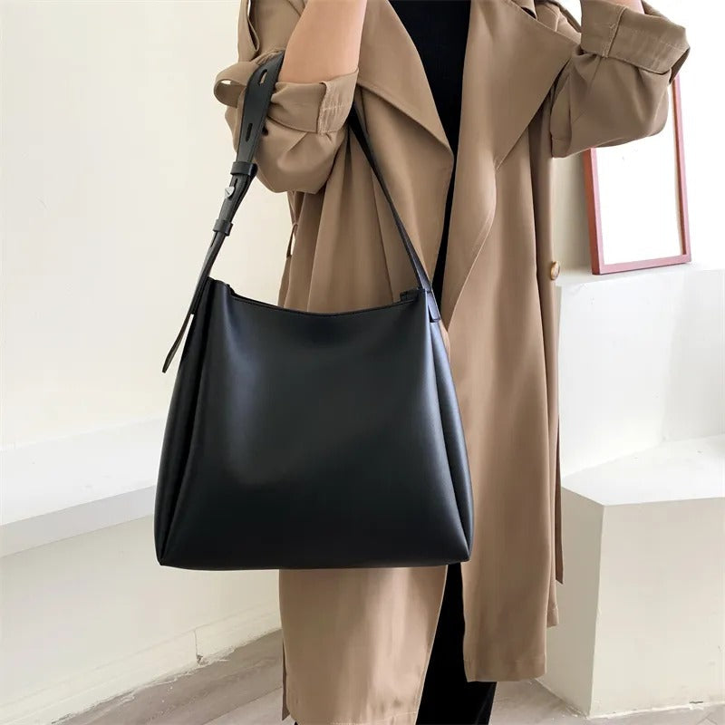 Delphine grand tote in black carried at the side