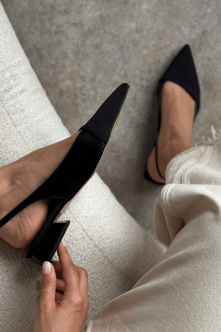 Black slingback ballet flat, close-up of low block heel and strap