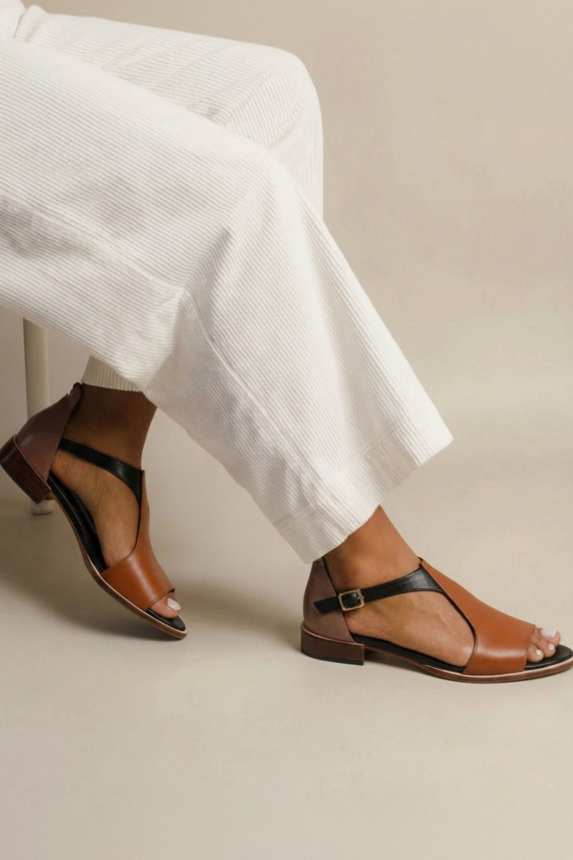Brown summer sandals with black T-bar and buckled ankle strap, worn with white trousers