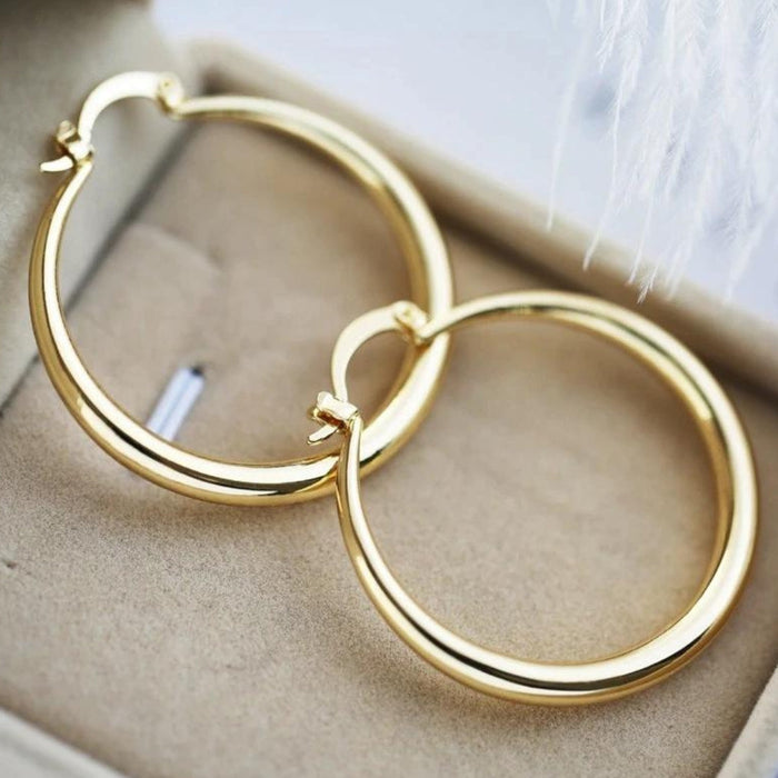 Timeless gold statement hoop earrings in a gift box, close-up angled view